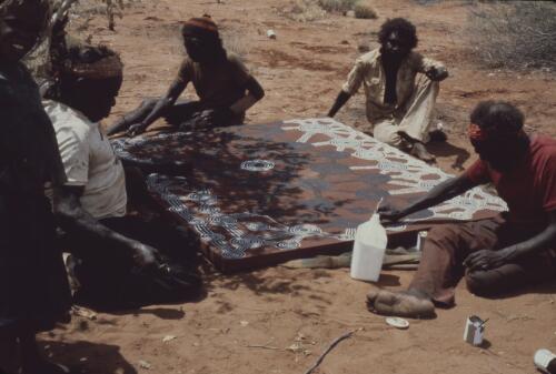 Artists working on a group painting, Papunya Tula, Northern Territory, 1976 [transparency] / Penny Tweedie