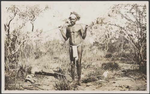Aboriginal man standing holding a large oval fishing net, 1914 [picture] / Frank Hurley