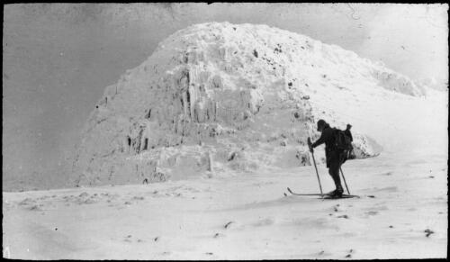 A skier in front of a snow covered rocky bluff, Victoria, approximately 1920 / Robert Wilkinson