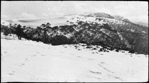 Footsteps in the snow leading to a lone figure looking at a mountain, Victoria, approximately 1920 / Robert Wilkinson