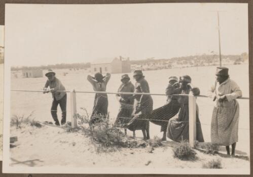 Group of Aboriginal men and women standing next to a fence, Koonibba Mission Station, South Australia