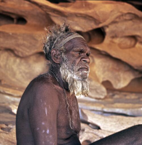 A Pitjantjatjara man sitting in a rock cave, Uluru, Northern Territory, approximately 1966 / Robin Smith