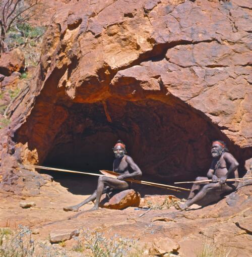 Aboriginal Australian tribal men Mick and Pomby sitting at the entrance of a cave, N'Dhala Gorge, Northern Territory, 1967 / Robin Smith