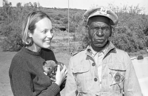 Aboriginal Australian man Tiger Tjalkaleri with a female visitor who is holding a dingo pup, Angas Downs, Northern Territory, 1965 / Robin Smith