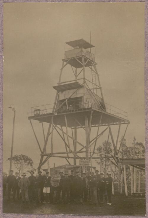 Group of internees standing in front of a watchtower at the internment camp at Holsworthy, New South Wales, 1918 or 1919 / Carl Schiesser