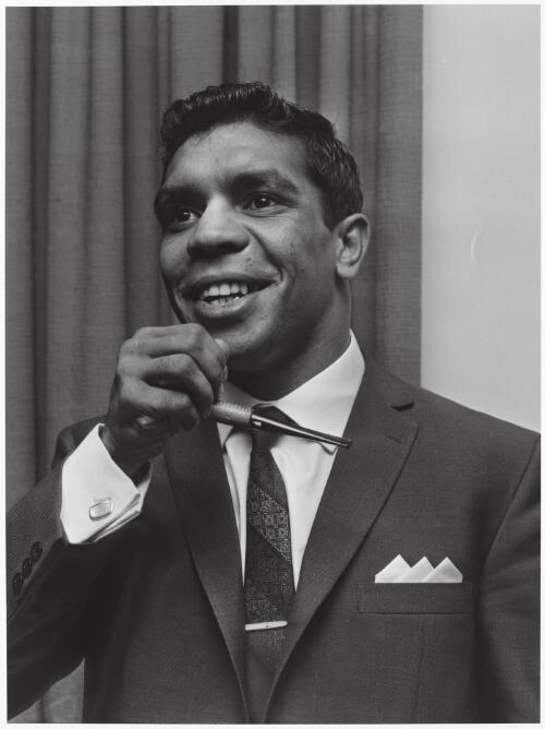 Lionel Rose, world champion Bantamweight boxer holding a pipe, Sydney Airport, 1968 / Mervyn Bishop