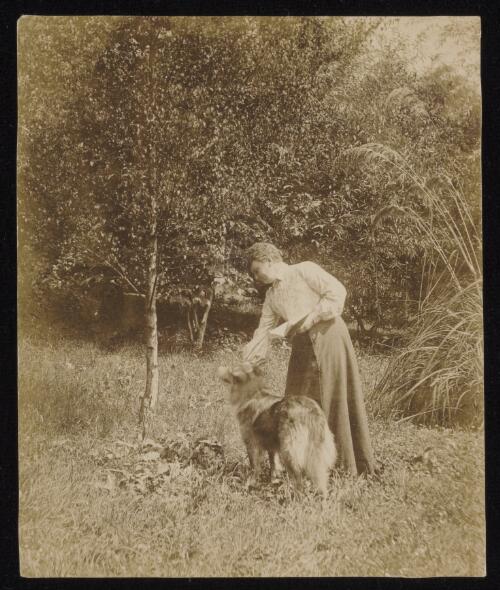 Susanne Gether feeding her dog, approximately 1896