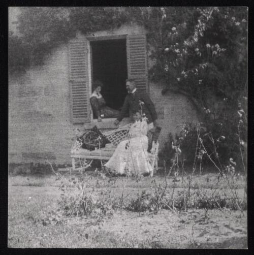 Two wowen and a man standing by a window with wooden shutters, Sydney?, approximately 1905