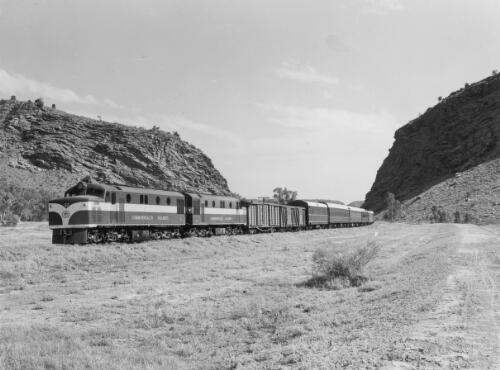 The narrow gauge Ghan approaching Alice Springs through Heavitree Gap behind a brace of NSU-class diesel electrics No. 57 and 58, Northern Territory, ca. 1968 [picture] / Australian Information Service