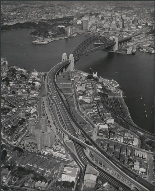 Aerial view of New South Wales government railways North Shore line, Harbour Bridge, Milson's Point station, and Lavender Bay car sidings, Sydney, 1963 [picture]