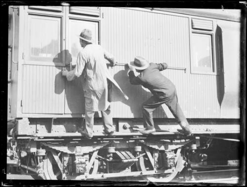 Two men trying to open the door of a goods train, New South Wales, ca. 1930 [picture]