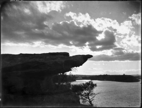 [Unidentified harbour scene with overhanging rock in foreground] [picture] / [Frank Hurley]