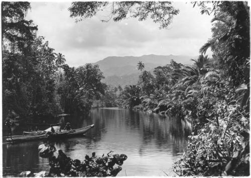 [Three figures in a canoe at a curve in a river, with jungle and mountains beyond] [picture] : [Pearls and savages] / [Frank Hurley]