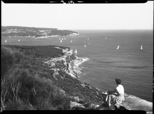 Scene looking to heads from Dobroyd Lookout [woman on rocks watching boats, two headlands, Sydney Harbour] [picture] : [Manly, New South Wales] / [Frank Hurley]