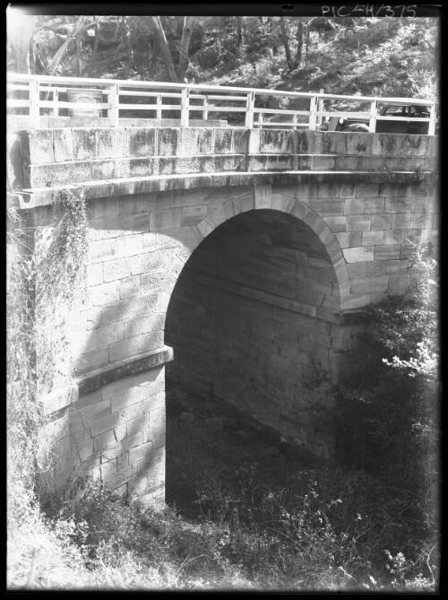 [Sandstone single arched road bridge over river, with wooden railings, and car 225-311] [picture] : [Australia] / [Frank Hurley]