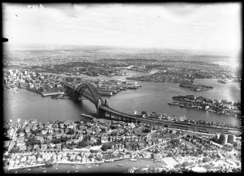High shot showing Bridge & looking up harbour, NS in foreground [Sydney Harbour Bridge and North Sydney] [picture] : [Sydney, New South Wales, Aerial] / [Frank Hurley]