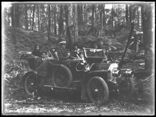 [Man in uniform, woman and three children in an early car in rainforest, Hurley family?] [picture] / [Frank Hurley]