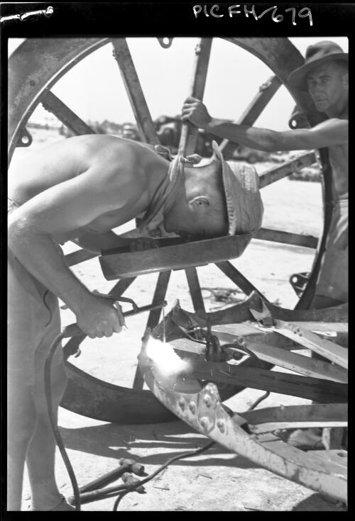 Australian soldiers, one welding a traversing stand, one with a traversing stand for a 25-pounder field gun, Egypt?, ca. 1941 [picture] / [Frank Hurley]