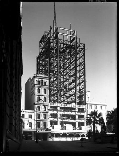 [Steel frame of AWA Building, York Street, rising between old buildings, Mangovite Belting Ltd. and Occidental, Sydney] [picture] : [Sydney buildings, New South Wales] / [Frank Hurley]