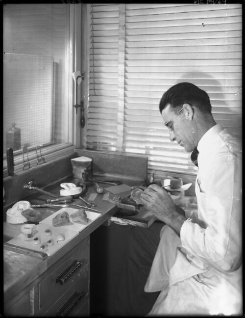 Making plastic ears and eyes [craftsman adding finishing touches, 1940s] [picture] : [Sydney, New South Wales] / [Frank Hurley]