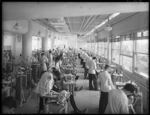 Dental clinic showing machines [senior students, teaching staff and patients, Sydney Dental Hospital, 1940s] [picture] : [Sydney, New South Wales] / [Frank Hurley]