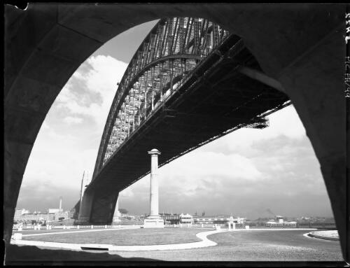 Dramatic study of Bridge through small arch [Sydney Harbour Bridge with column from East side at North Sydney] [picture] : [Sydney Harbour, New South Wales] / [Frank Hurley]