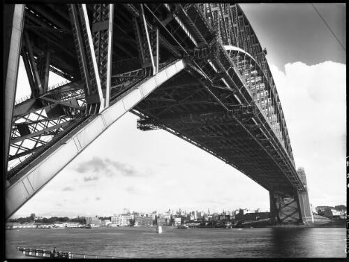 Bridge framing vista of City [Circular Quay, Bennelong Point, framed by a roadway and a span of the Sydney Harbour Bridge] [picture] : [Sydney Harbour, New South Wales] / [Frank Hurley]