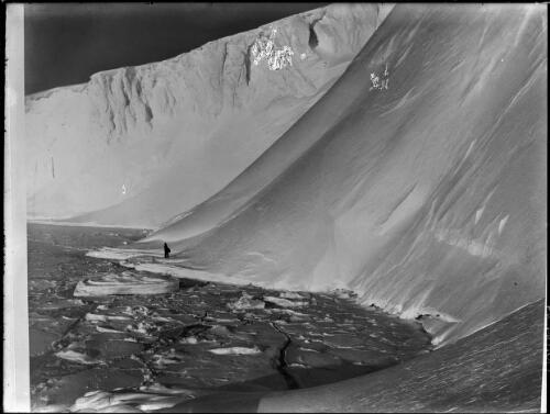 Dr Leslie H. Whetter negotiating a dangerous stretch of broken ice along the coastal downfalls near the Winter Quarters, at the foot of the Great Ice Barrier, Commonwealth Bay, Adelie Land, Australasian Antarctic Expedition, 1911-1914 [picture] / Frank Hurley