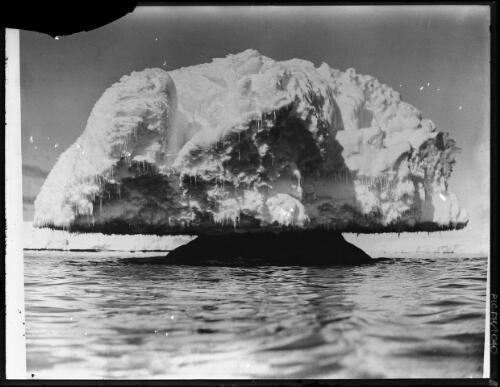 A gigantic mushroom of the Mackellar Archipelago, formed by blizzards pelting frozen sea spray on to an exposed reef - the mushroom grows until the summer when it splits up and disintegrates [Adelie Land, Australasian Antarctic Expedition, 1911-1914] [picture] : [Antarctica] / [Frank Hurley]
