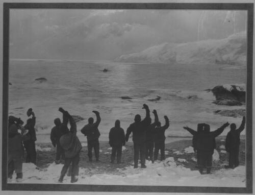 [Thirteen men on Elephant Island wave farewell to Sir Ernest Shackleton, Frank Worsley, Timothy McCarthy A.B., Tom Crean, Harry McNeish, the carpenter, and Vincent, the boatswain, as they leave for South Georgia, Monday, 24 April 1916] [picture] : [Antarctica] / [Frank Hurley]