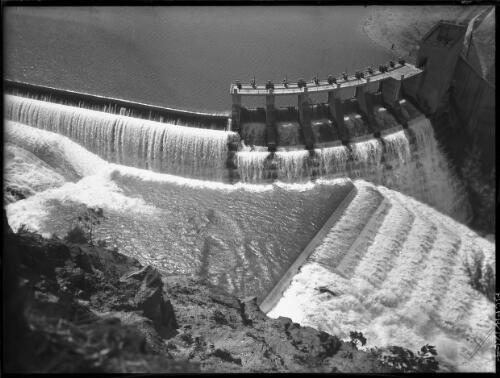 [Eildon Weir, from the air, with water pouring down dam wall] [picture] : [Victoria] / [Frank Hurley]