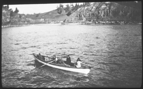 [Seven people in a long boat with staves nearing a beach surrounded by high cliffs] [picture] : [Norfolk Island] / [Frank Hurley]