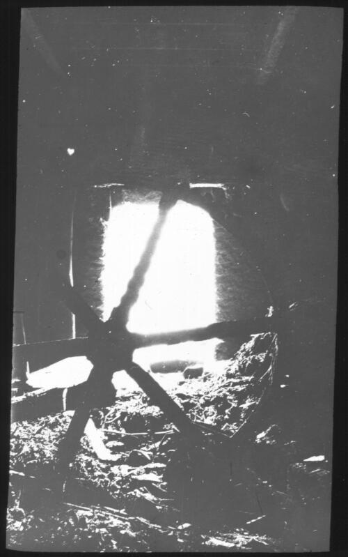 [A large wheel silhouetted against the light coming through a doorway into a cellar or dark room] [picture] : [Norfolk Island] / [Frank Hurley]