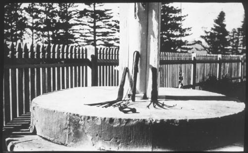 [A whipping post and whips on a large round of wood, Norfolk Island] [picture] : [Norfolk Island] / [Frank Hurley]
