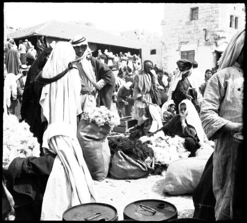 Beersheba Palestine [crowded local market with sacks of produce, drums, and crates] [picture] / [Frank Hurley]