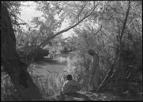 [Sitting on the bank of the Jordan River among trees, Jericho, ca. 1942] [picture] / [Frank Hurley]