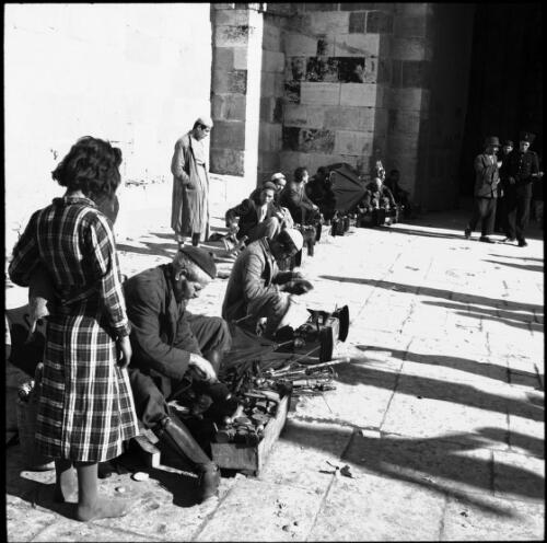 Street vendors near Jaffa Gate Jerusalem [with figures and boxes, long shadows and a figure in checked dress] [picture] / [Frank Hurley]