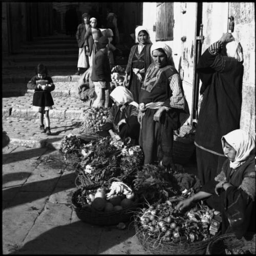 Street vendors near Jaffa Gate Jerusalem [figures with baskets full of fruit and a child in a short dress near wide steps] [picture] / [Frank Hurley]
