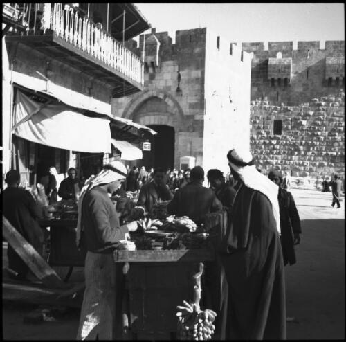 Street vendors near Jaffa Gate Jerusalem [figures with wares on tables] [picture] / [Frank Hurley]
