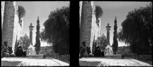Jerusalem [two figures sitting on the ground beside a wall, with a minaret in the distance] [picture] / [Frank Hurley]