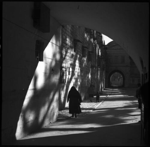 [Figure walking along an arched street] [picture] / [Frank Hurley]