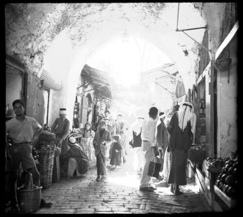 Street scenes in Jerusalem [narrow street with shops and produce] [picture] / [Frank Hurley]