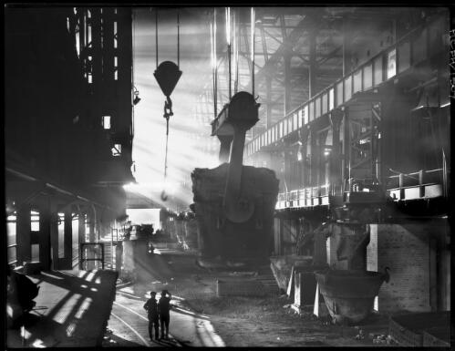 An eighty-ton ladle in the open hearth pit being carried to the furnace, B.H.P. Steelworks, Newcastle, New South Wales [picture] / Frank Hurley