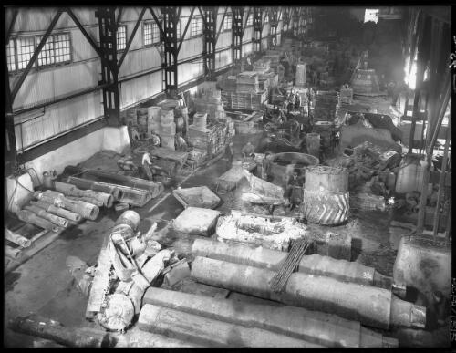 [The working floor of an industrial plant, with figures and machinery] [picture] : [Newcastle, New South Wales] / [Frank Hurley]