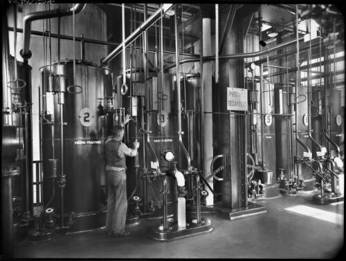 [Fractionating plant? figure operating tap with product decanters] [picture] : [Industry] / [Frank Hurley]