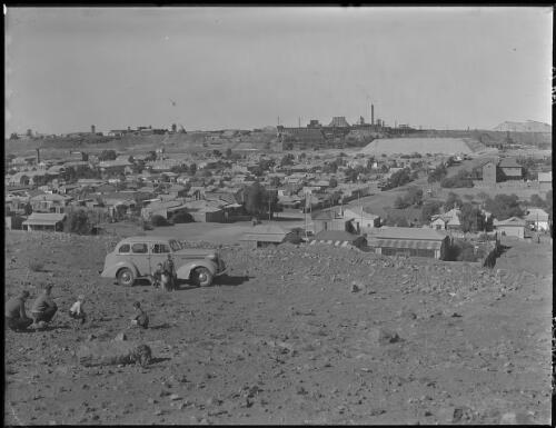 [Broken Hill township, with a car and several figures including children in the foreground] [picture] : [Broken Hill, New South Wales] / [Frank Hurley]
