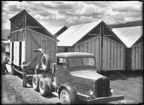 Prefab houses on transporters [Thornycroft truck and six men, Kiewa, December 1947] [picture] : [State Electricity Commission of Victoria] / [Frank Hurley]