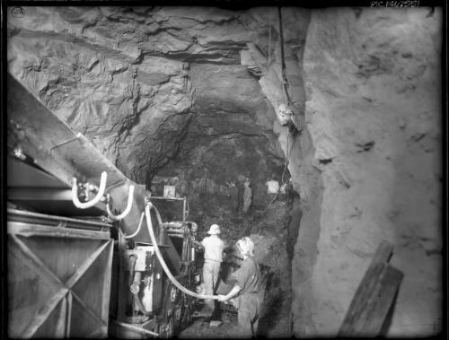 Excavating No.4 P.S. tunnel [men with power-drilling equipment, power station, Kiewa, December 1947] [picture] : [State Electricity Commission of Victoria] / [Frank Hurley]