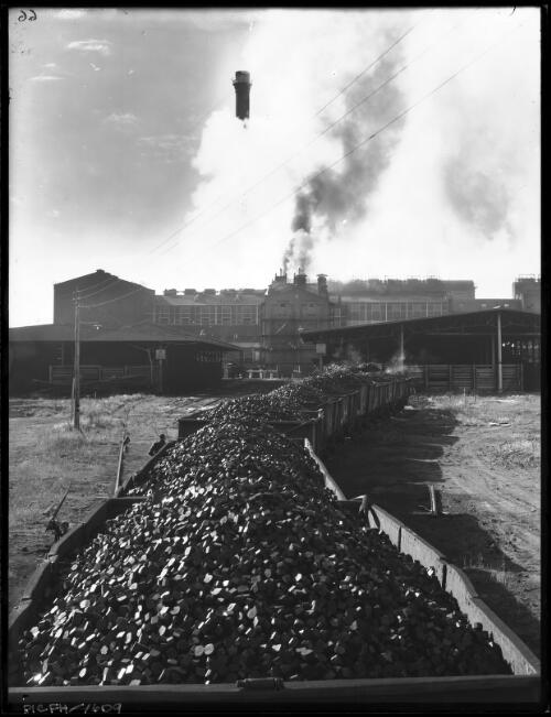 BF with trucks of briquettes in fg [Briquette Factory, Yallourn, Victoria, December 1947] [picture] : [State Electricity Commission of Victoria] / [Frank Hurley]