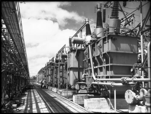 Main transformer bank [with figures, power station, Yallourn, Victoria, December 1947] [picture] : [State Electricity Commission of Victoria] / [Frank Hurley]